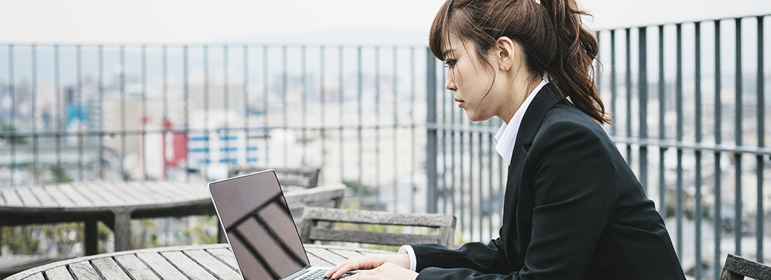 En kvinne i Kyoto i Japan, som jobber utendørs på en laptop